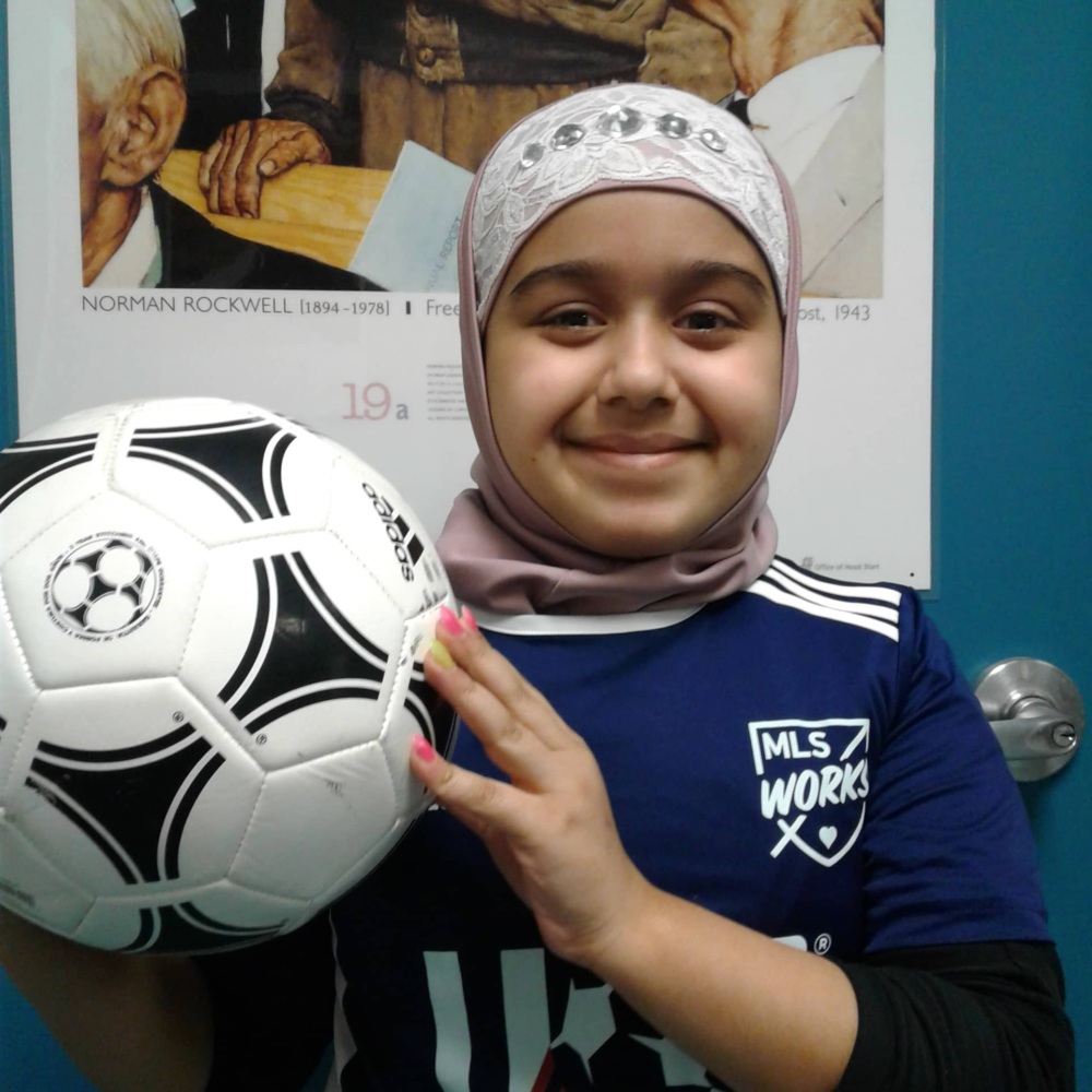 Girl smiling and holding soccer ball